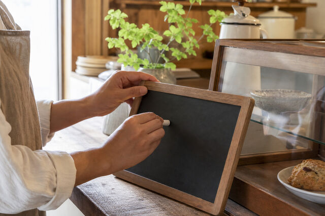 カフェの店主が黒板メニューを書く手元